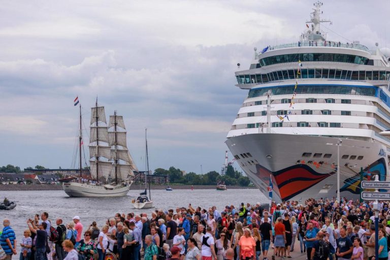 Luxuriöses Kreuzfahrtschiff im Sonnenuntergang vor tropischen Inseln.